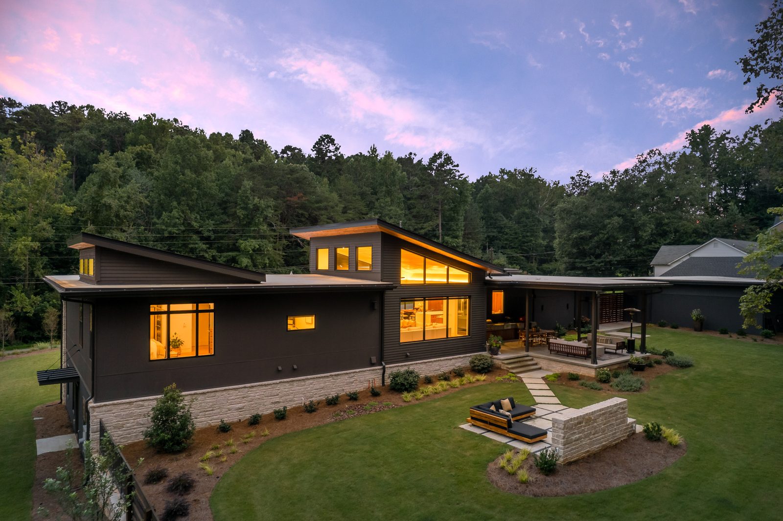 Rear elevation at twilight with the fire-pit lounge — The Ortiz Home, custom home built by Ironwood Construction Group in Sugar Hill, Georgia