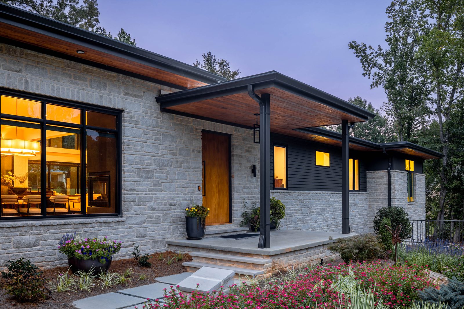 Front entry at dusk with stone facade and wood door — The Ortiz Home, custom home built by Ironwood Construction Group in Sugar Hill, Georgia