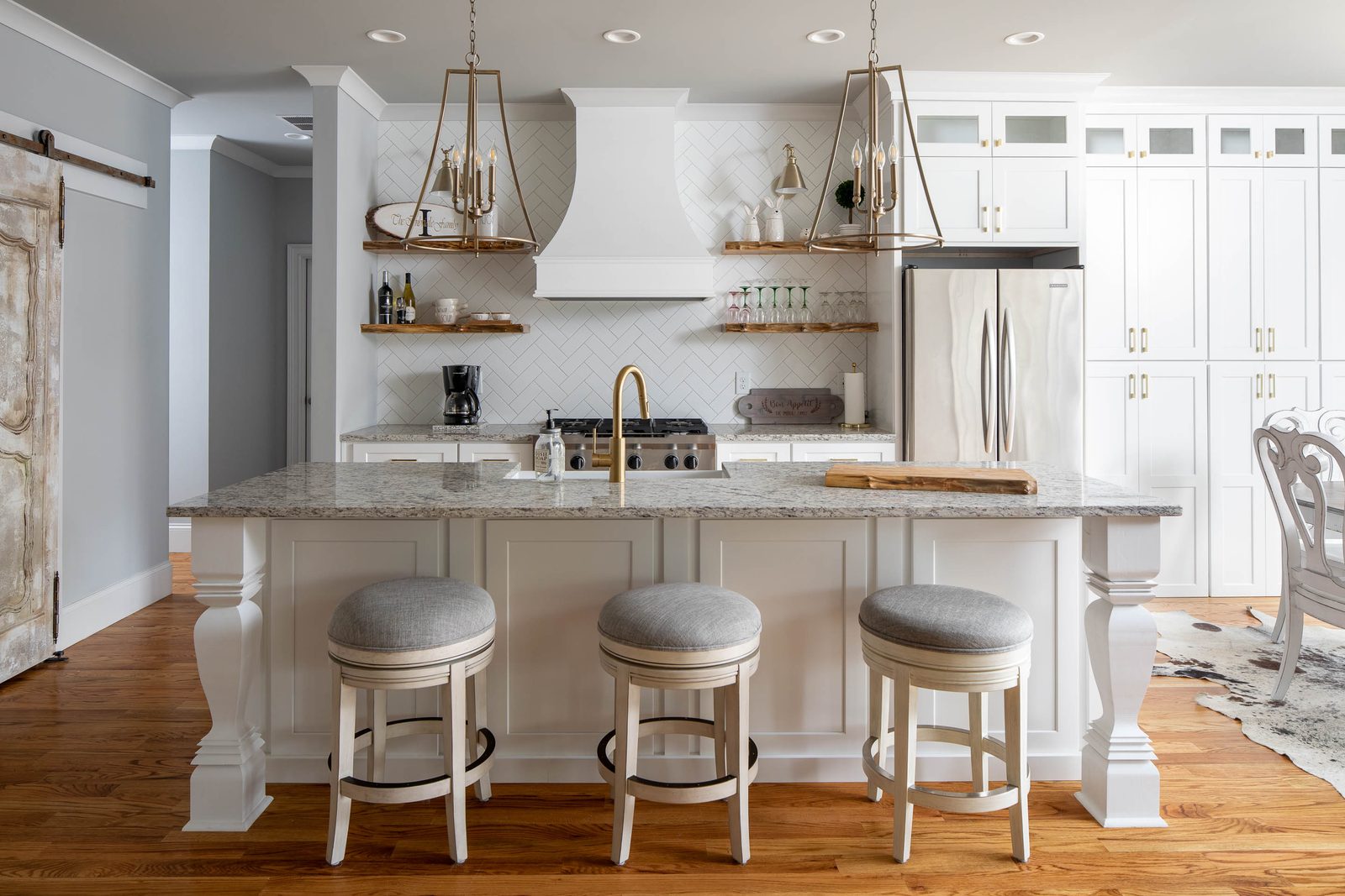 Kitchen with granite island, white cabinets and floating shelves — Imbriale, custom home built by Ironwood Construction Group