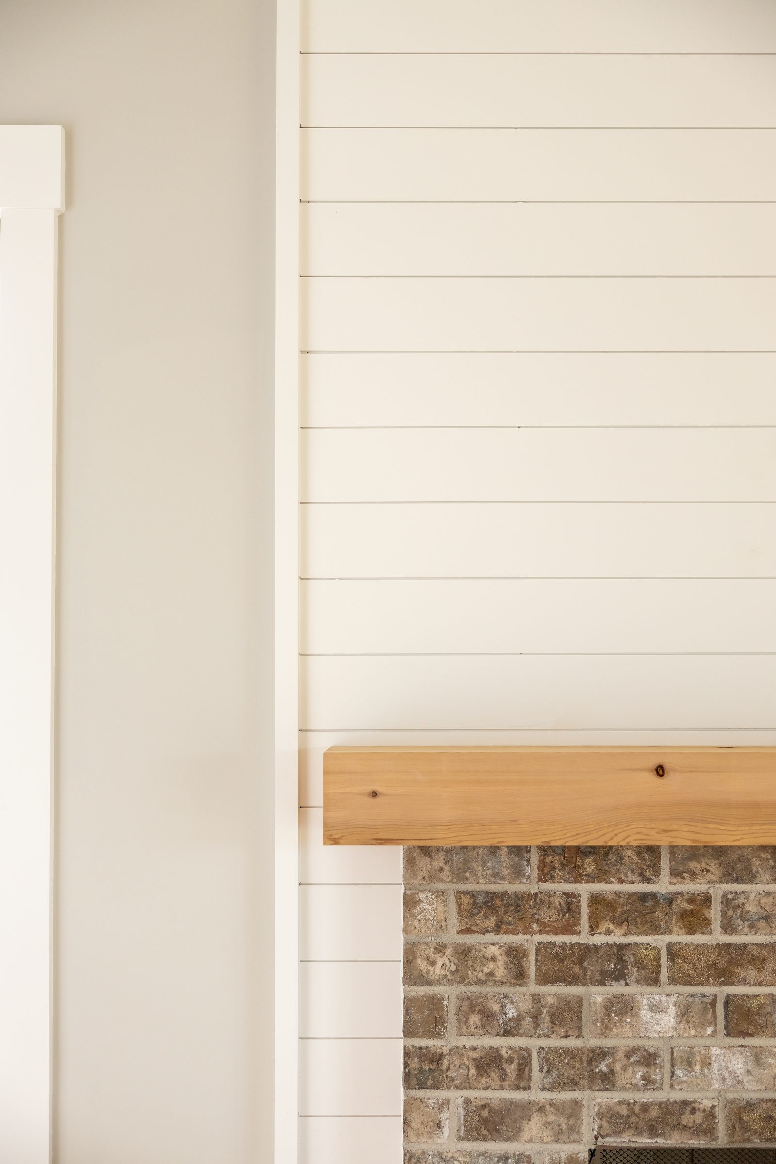 Shiplap chimney breast with wood mantel above brick — Shadburn Ferry, custom home built by Ironwood Construction Group in Buford, Georgia