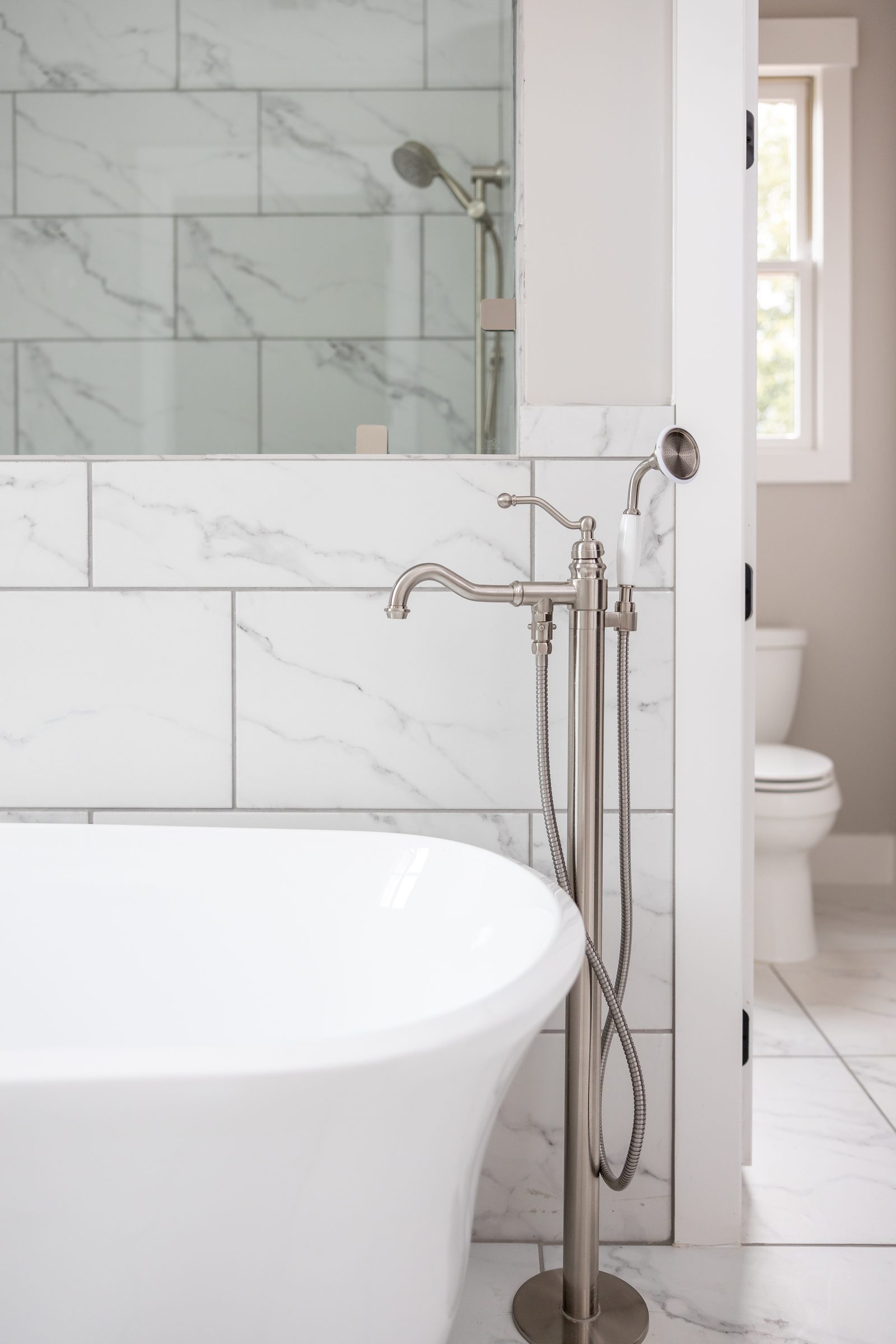 Freestanding tub beside the marble walk-in shower — Shadburn Ferry, custom home built by Ironwood Construction Group in Buford, Georgia